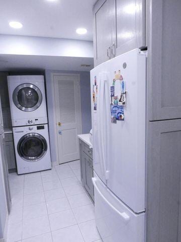 laundry room with laundry area, light tile patterned floors, stacked washer / drying machine, and recessed lighting