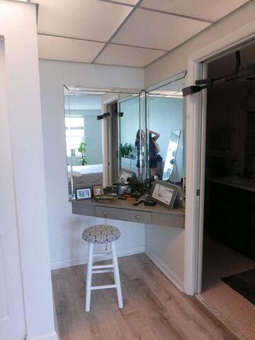 interior space featuring baseboards, a drop ceiling, and wood finished floors