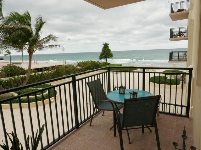 balcony with a water view and a view of the beach