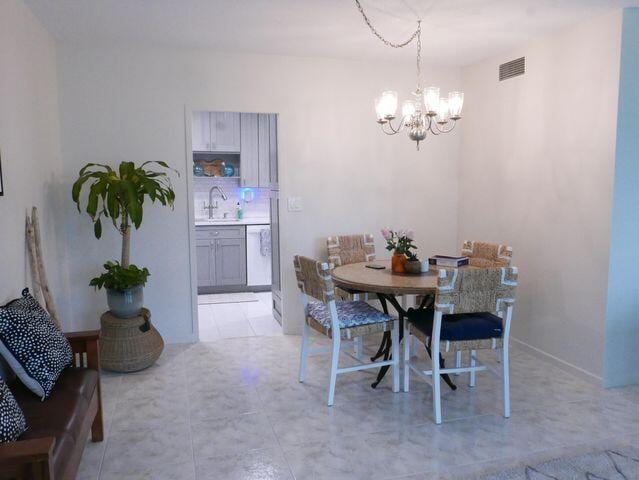 dining room featuring light tile patterned flooring, visible vents, and an inviting chandelier