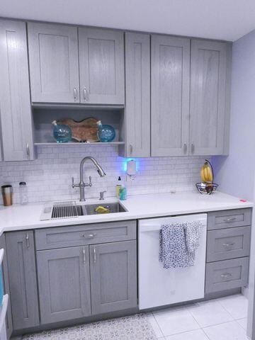 kitchen with a sink, open shelves, light countertops, and dishwasher