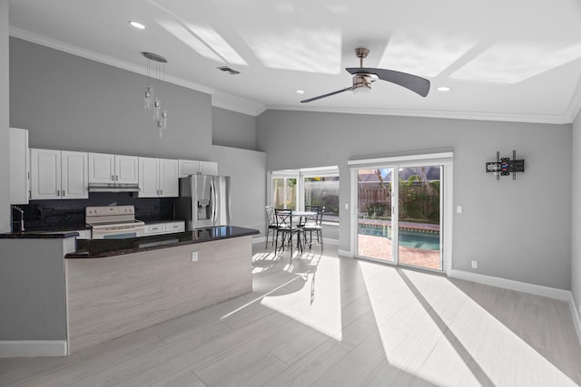 kitchen featuring dark countertops, electric range, white cabinetry, stainless steel fridge, and under cabinet range hood