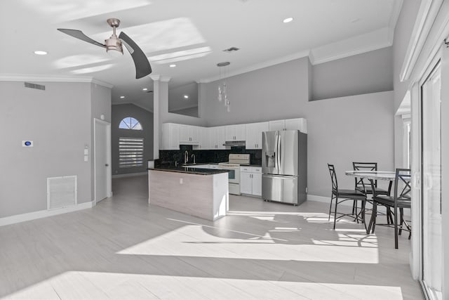 kitchen featuring stainless steel refrigerator with ice dispenser, dark countertops, white electric range, visible vents, and white cabinetry