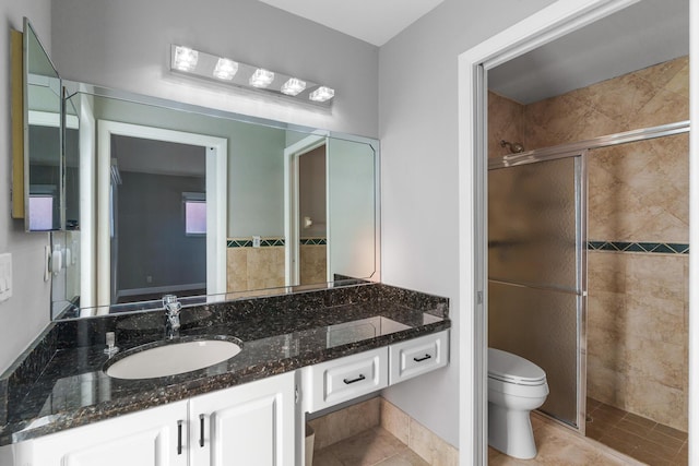 bathroom with toilet, tile patterned flooring, a shower stall, and vanity