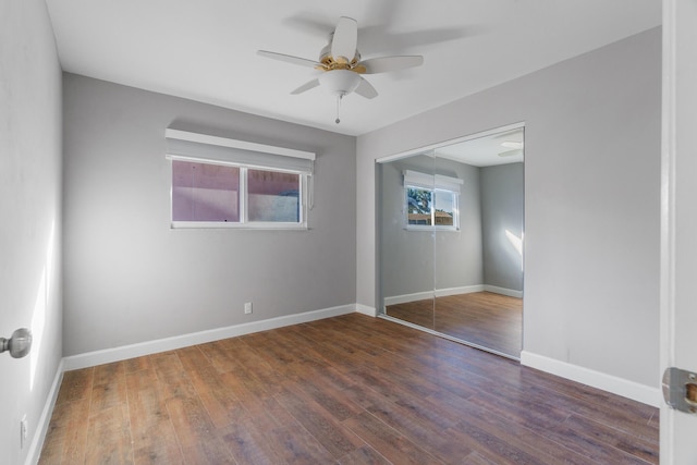 unfurnished bedroom with dark wood-type flooring, a closet, a ceiling fan, and baseboards