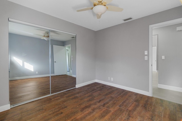 unfurnished bedroom featuring dark wood finished floors, a closet, visible vents, a ceiling fan, and baseboards