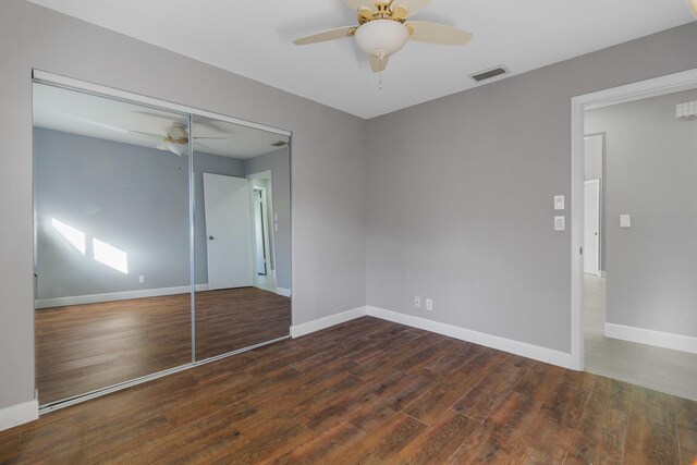 unfurnished bedroom with dark wood-type flooring, visible vents, baseboards, and multiple windows