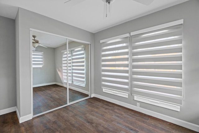 interior space with dark wood-style flooring, a closet, a ceiling fan, and baseboards