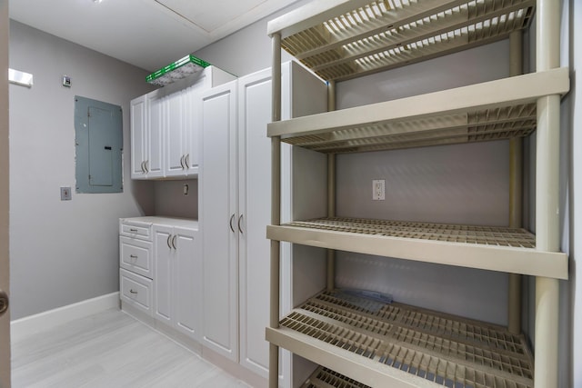 laundry area featuring light wood-style floors, electric panel, and baseboards