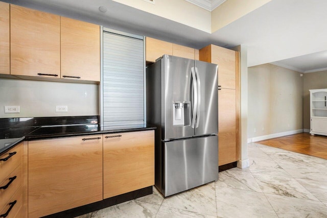 kitchen featuring crown molding, stainless steel refrigerator with ice dispenser, dark countertops, light brown cabinets, and baseboards