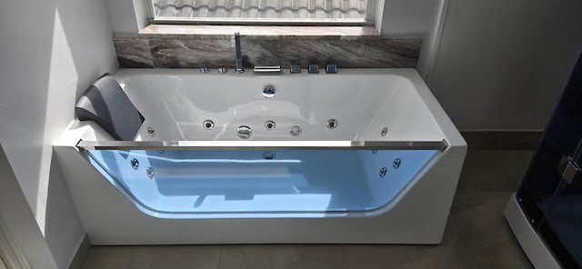 bathroom with tile patterned flooring and a tub with jets