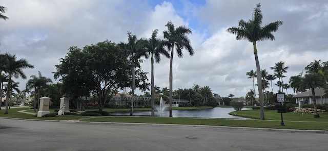 view of road featuring traffic signs, a water view, curbs, and sidewalks