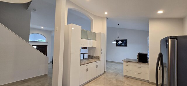 kitchen featuring glass insert cabinets, freestanding refrigerator, white cabinets, and hanging light fixtures