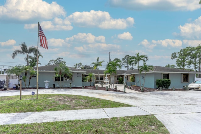 single story home featuring driveway, a front lawn, and stucco siding