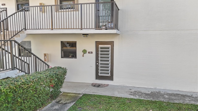 property entrance with a balcony and stucco siding