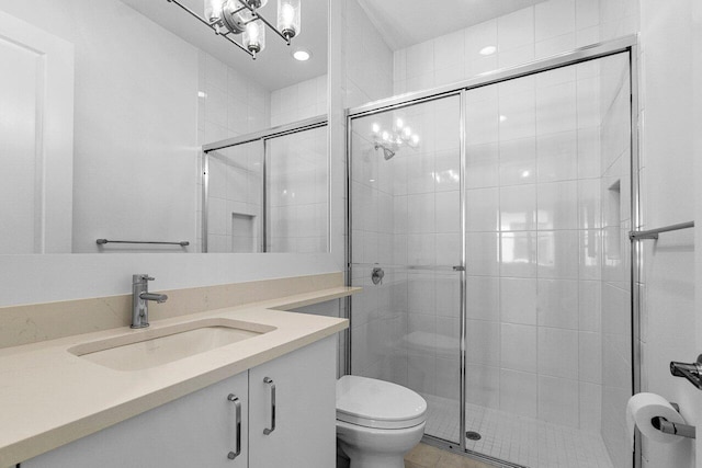 full bathroom with a chandelier, a shower stall, vanity, and toilet