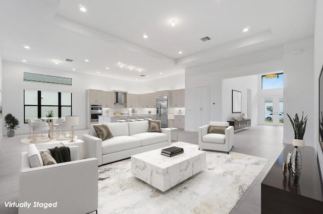 living area with visible vents, french doors, a raised ceiling, and a towering ceiling