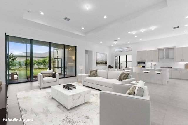 living room with light tile patterned floors, a raised ceiling, visible vents, and recessed lighting