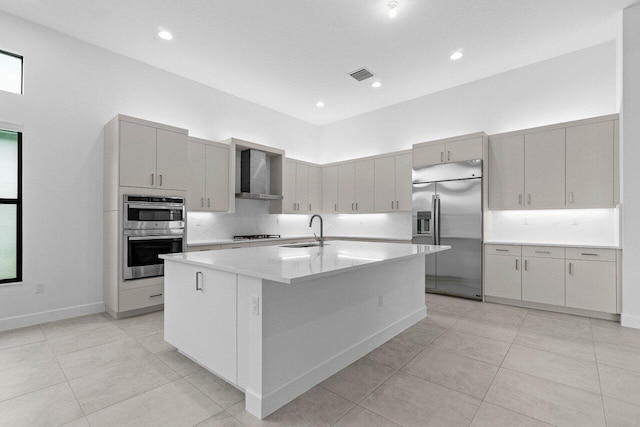 kitchen featuring a kitchen island with sink, a sink, visible vents, appliances with stainless steel finishes, and wall chimney exhaust hood