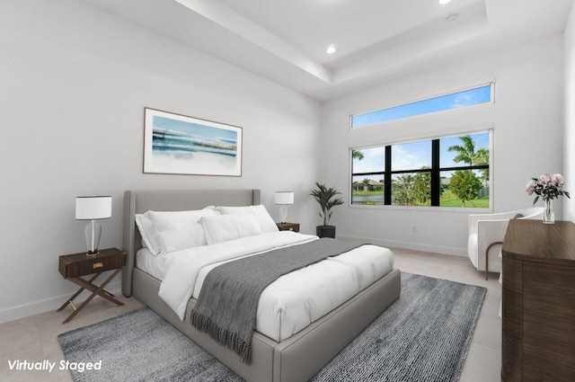 bedroom with a tray ceiling, light tile patterned flooring, and baseboards