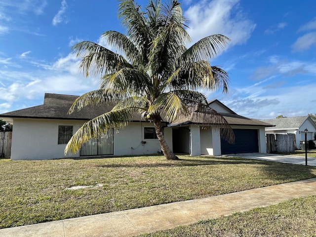 view of front of property featuring driveway, stucco siding, an attached garage, fence, and a front yard