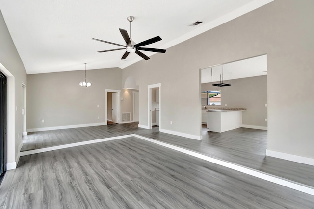 unfurnished living room featuring wood finished floors, visible vents, baseboards, and ceiling fan with notable chandelier