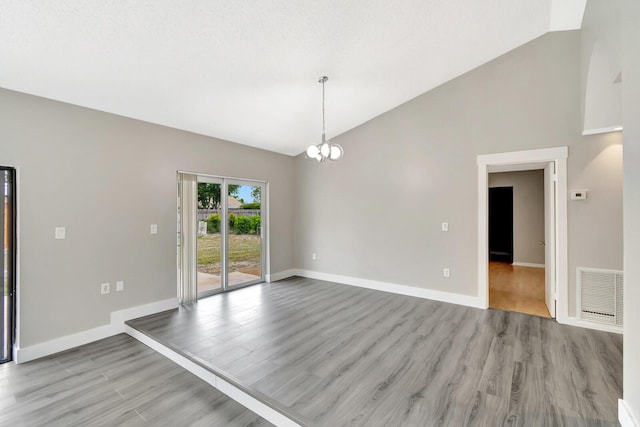 spare room featuring baseboards, visible vents, light wood finished floors, and an inviting chandelier