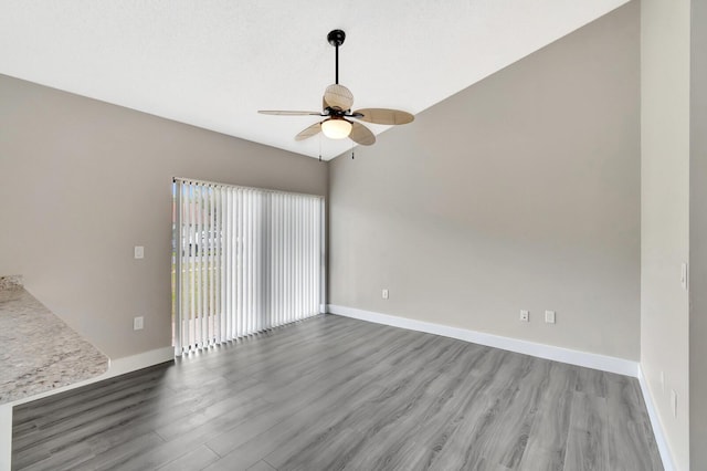 empty room with lofted ceiling, ceiling fan, baseboards, and wood finished floors