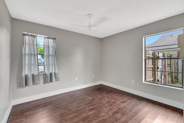 spare room with a healthy amount of sunlight, baseboards, and dark wood-style flooring