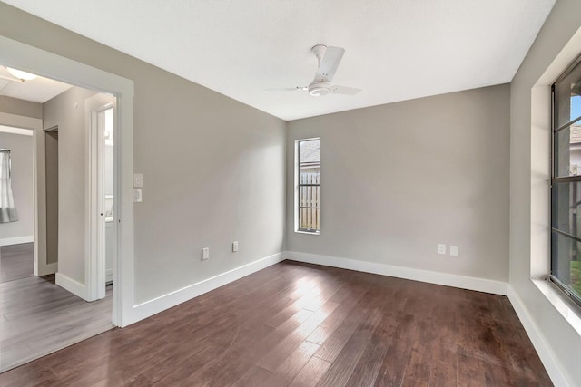 spare room featuring a ceiling fan, dark wood finished floors, and baseboards