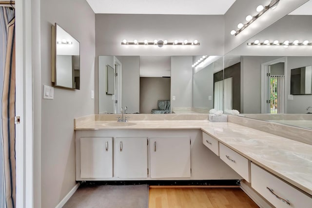 full bath featuring baseboards, wood finished floors, and vanity