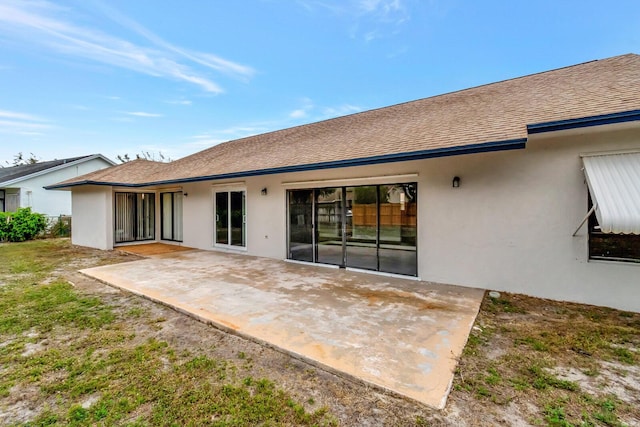 back of house with a patio, a shingled roof, and stucco siding