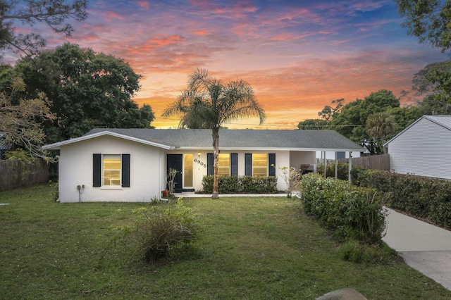 single story home with a shingled roof, fence, a lawn, and stucco siding