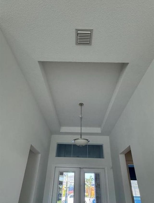 interior details featuring french doors, a raised ceiling, and visible vents