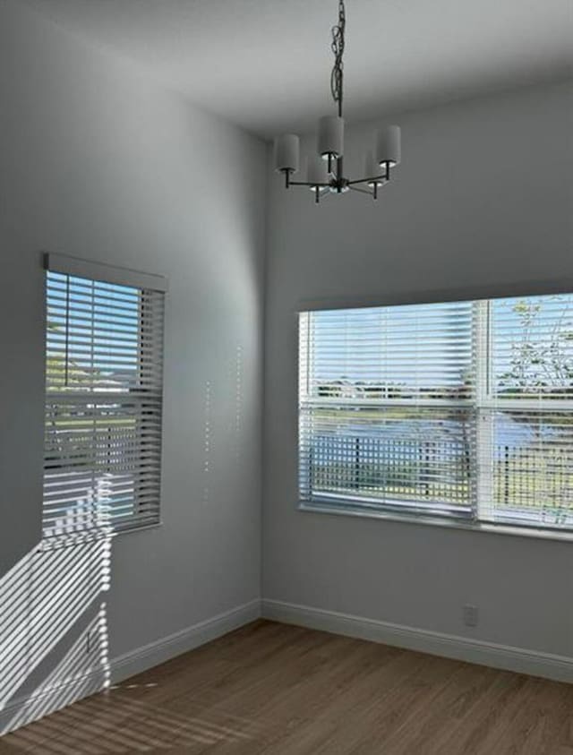 empty room featuring baseboards, a chandelier, and a wealth of natural light