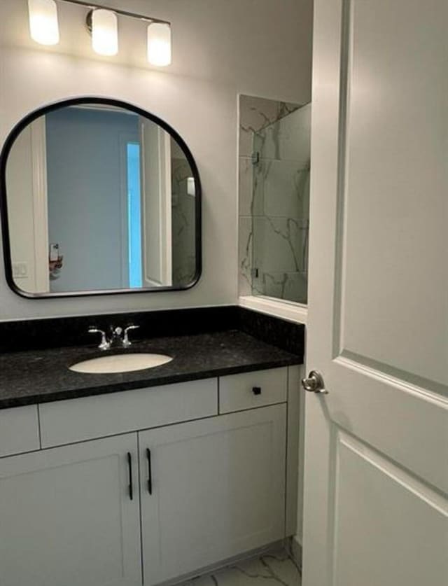 full bath featuring marble finish floor, a shower, and vanity