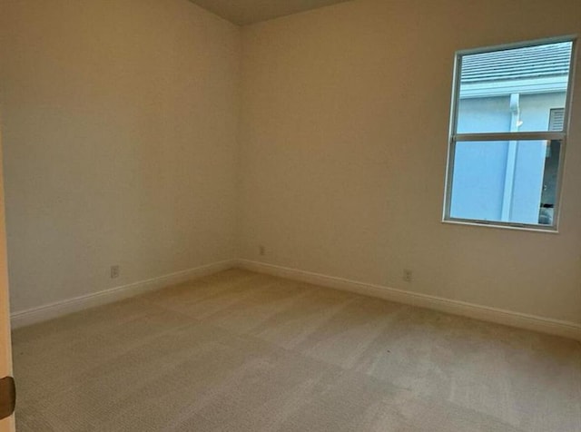 unfurnished room featuring carpet floors and baseboards