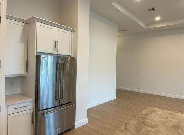 kitchen with visible vents, white cabinets, high end fridge, light countertops, and light wood finished floors