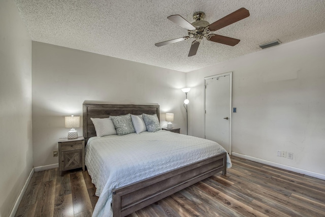 bedroom with a textured ceiling, ceiling fan, wood finished floors, visible vents, and baseboards