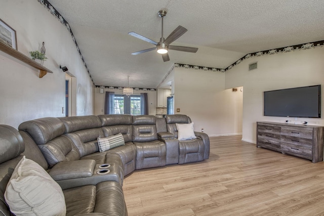 living area featuring visible vents, a ceiling fan, vaulted ceiling, a textured ceiling, and light wood-style floors