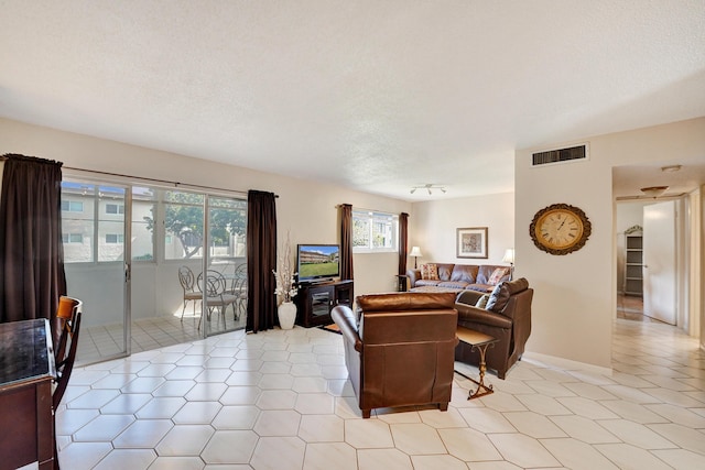 living room featuring visible vents, a textured ceiling, and light tile patterned floors