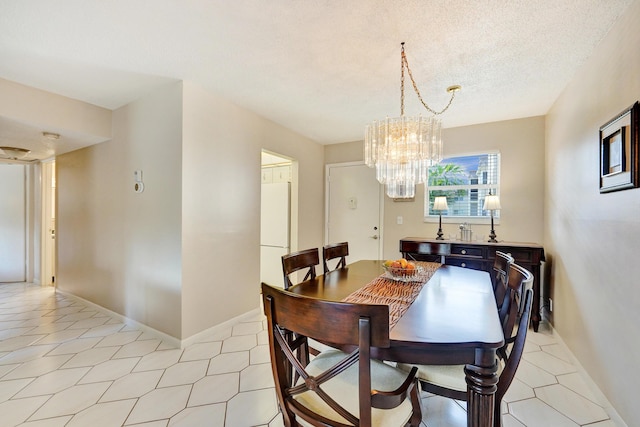 dining area with a chandelier, a textured ceiling, baseboards, and light tile patterned floors