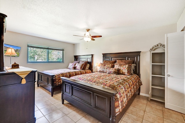 bedroom with light tile patterned floors, ceiling fan, and a textured ceiling