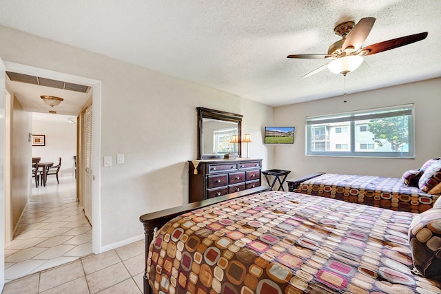 bedroom featuring visible vents, a ceiling fan, light tile patterned flooring, a textured ceiling, and baseboards