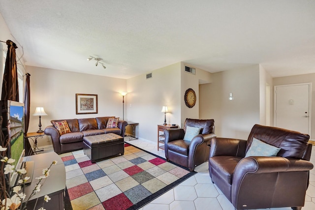 living room with a textured ceiling, light tile patterned floors, and visible vents