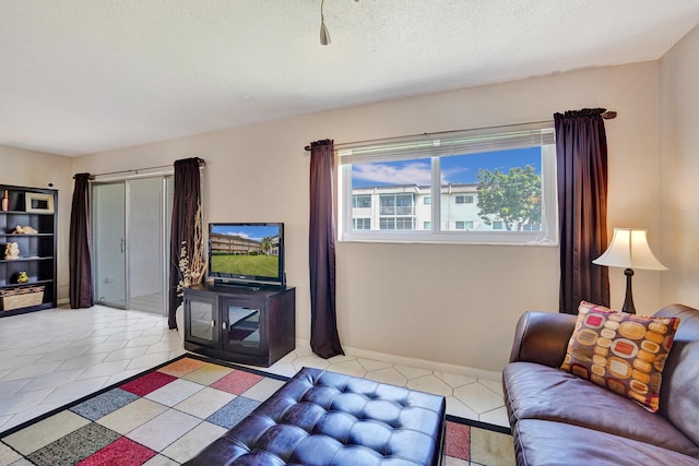 living room featuring a textured ceiling, baseboards, and light tile patterned floors