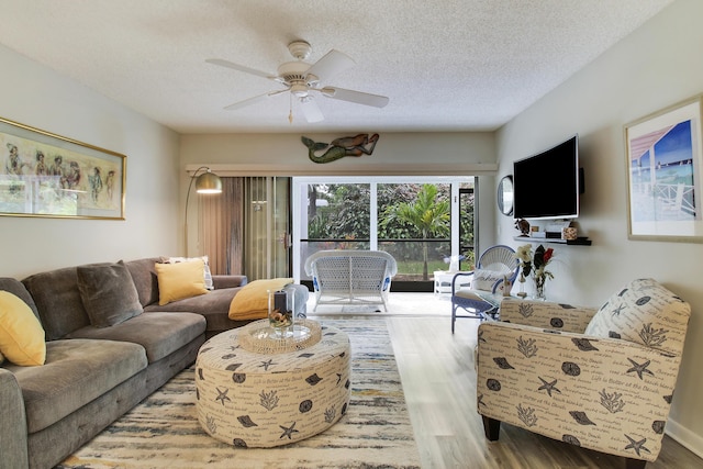 living area with a ceiling fan, a textured ceiling, and wood finished floors