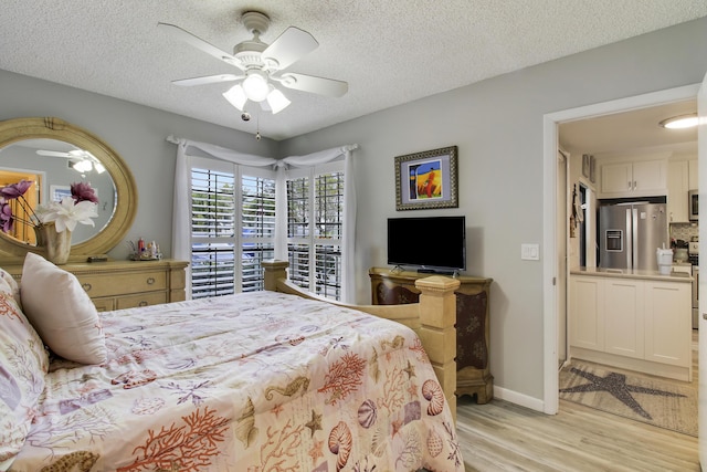 bedroom with baseboards, a ceiling fan, light wood-style flooring, a textured ceiling, and stainless steel refrigerator with ice dispenser