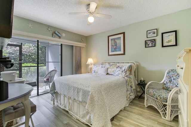 bedroom featuring access to exterior, a ceiling fan, a textured ceiling, and wood finished floors