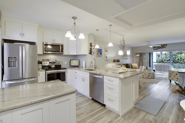 kitchen featuring stainless steel appliances, tasteful backsplash, open floor plan, a sink, and a peninsula